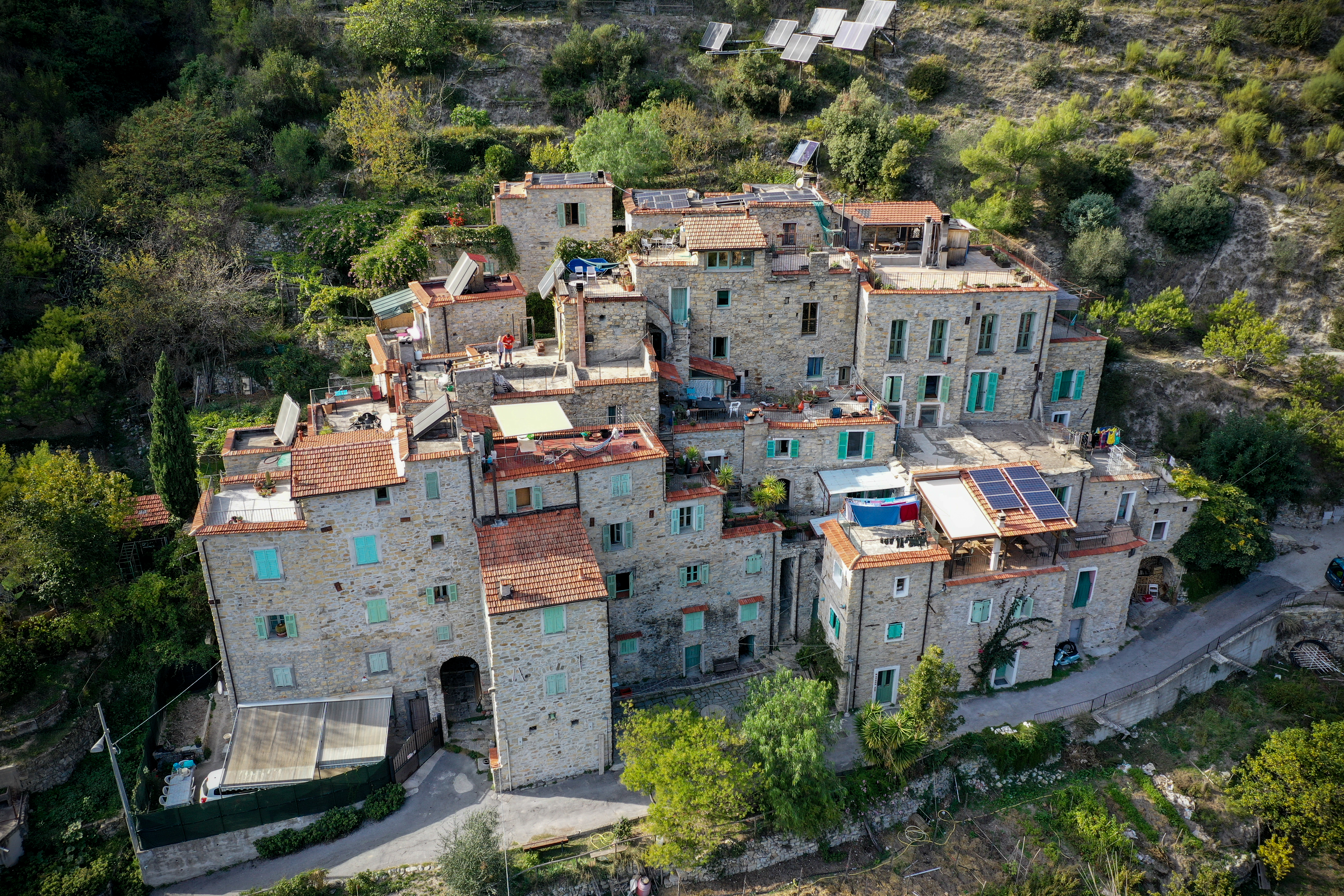 Aerial view of a stone village with solar panels on rooftops.