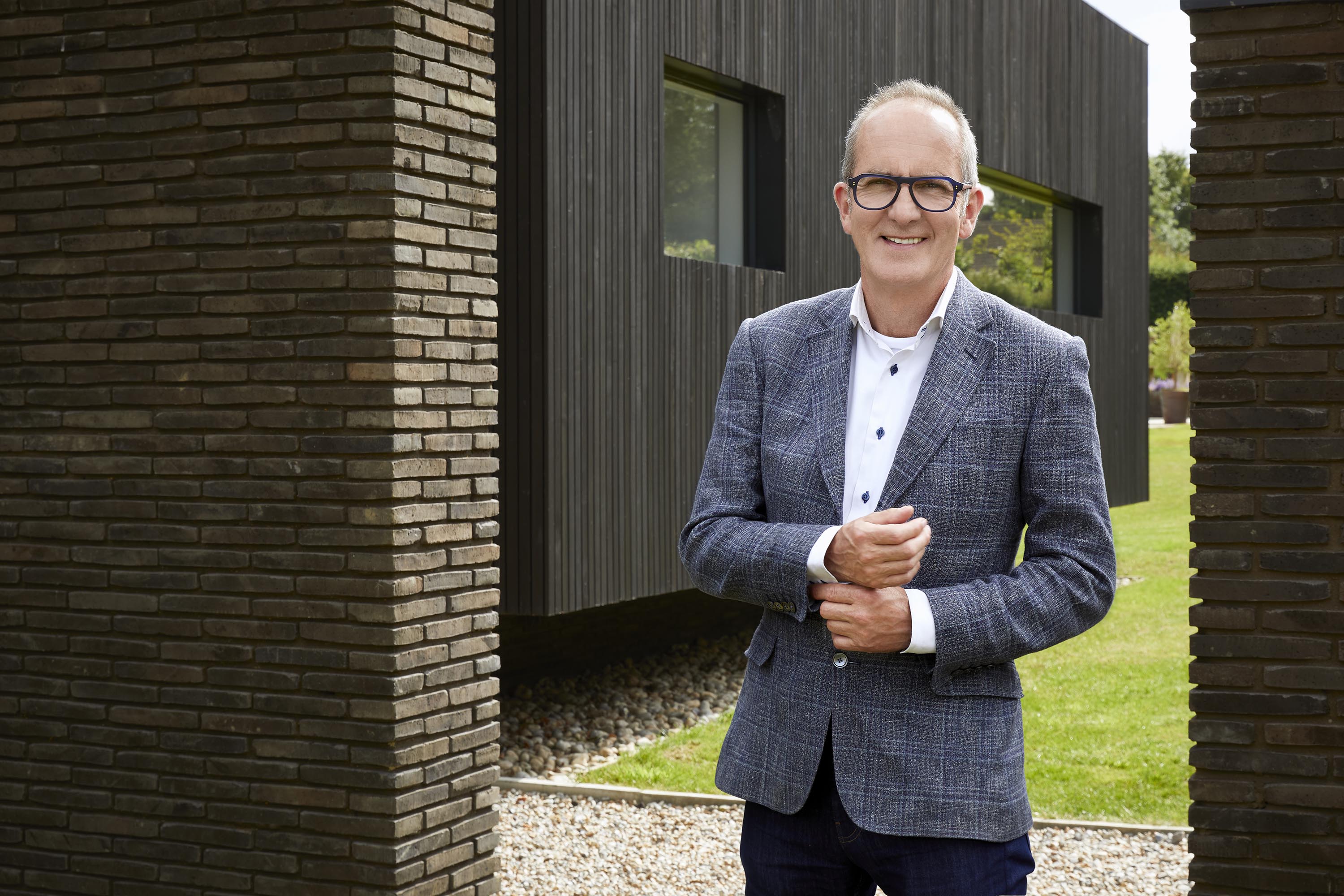 Kevin McCloud standing in front of a modern house.