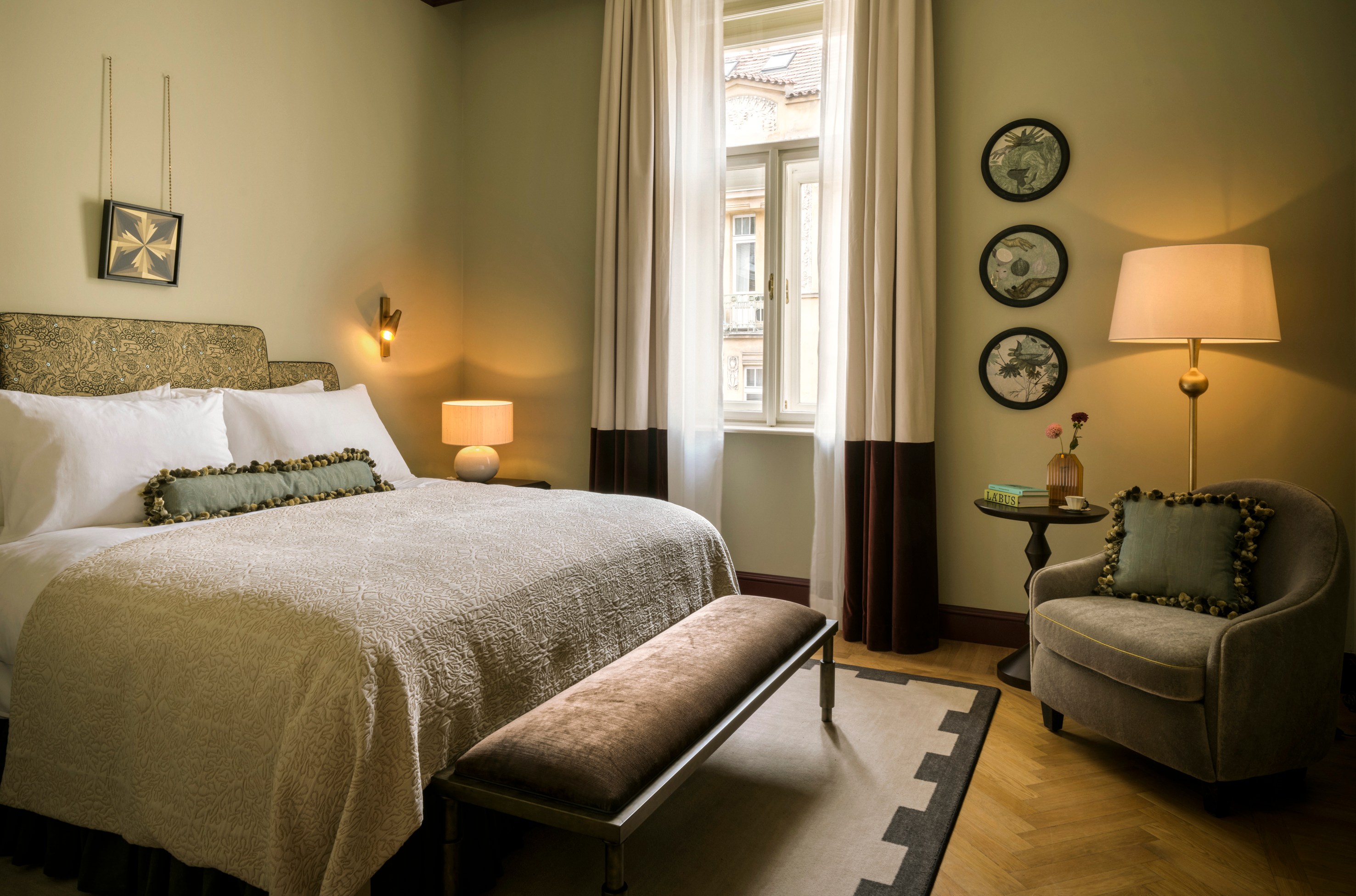 Hotel bedroom with a large bed, armchair, and patterned rug.