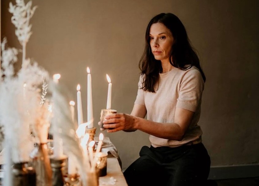 Woman lighting candles on a table.