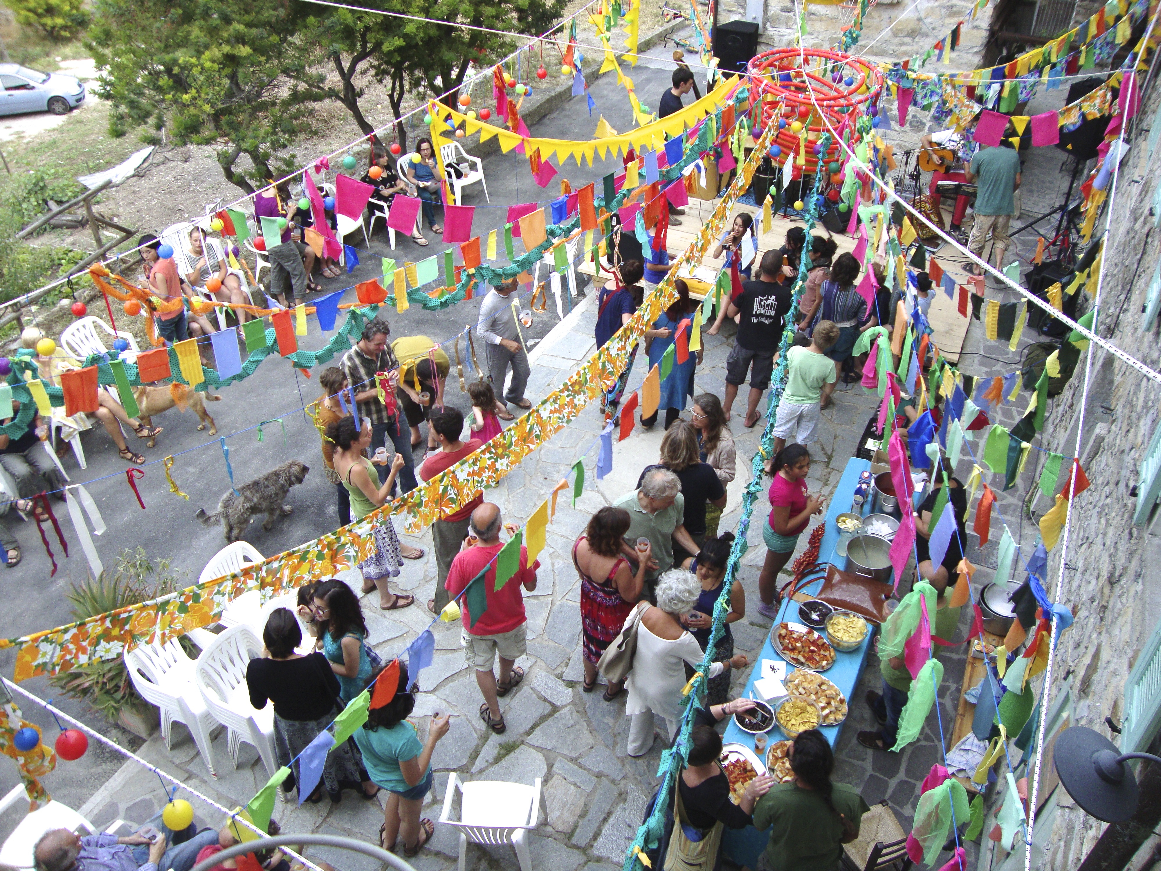 Aerial view of a lively outdoor party with colorful decorations and people socializing.