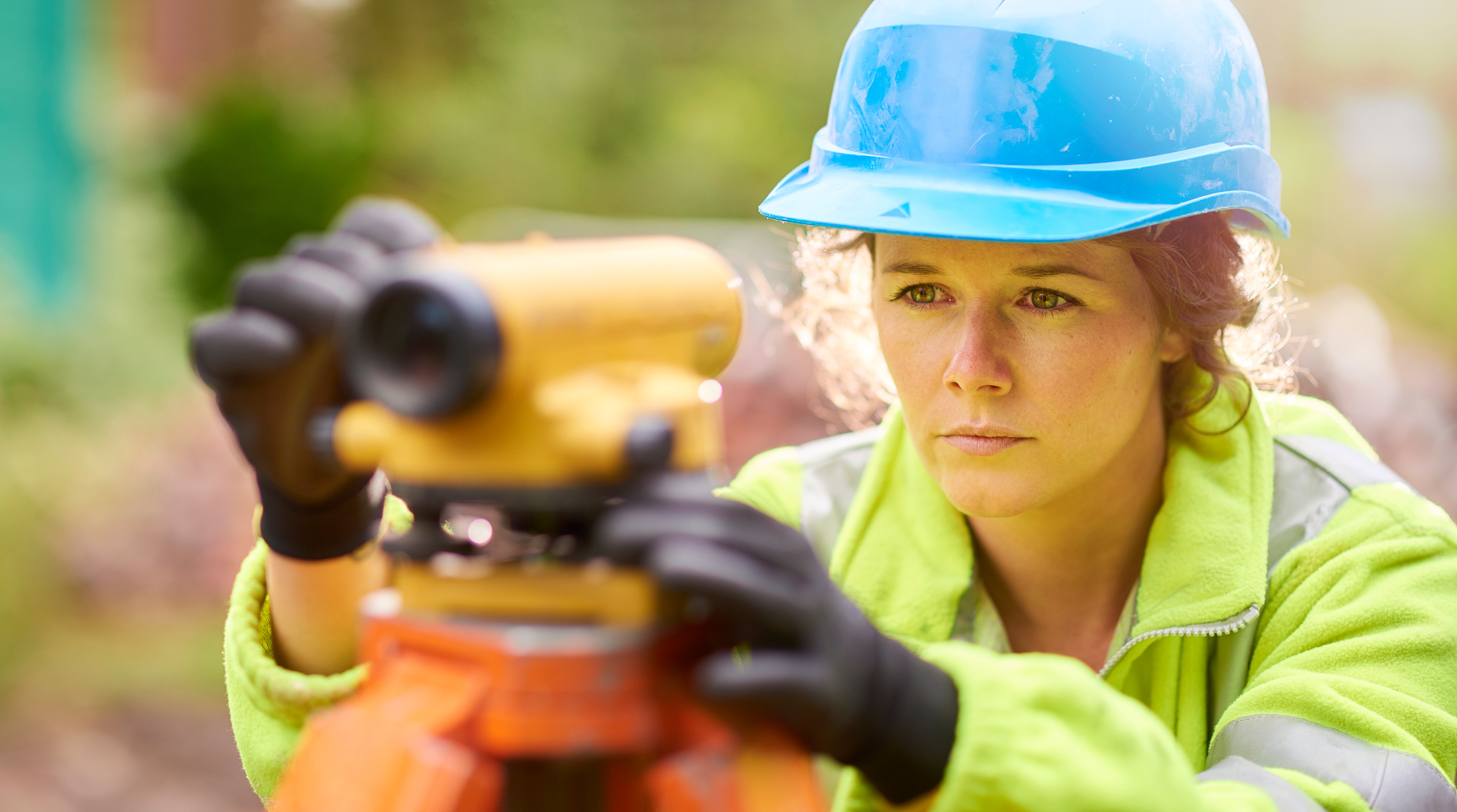 A female surveyor using a level on a building site.