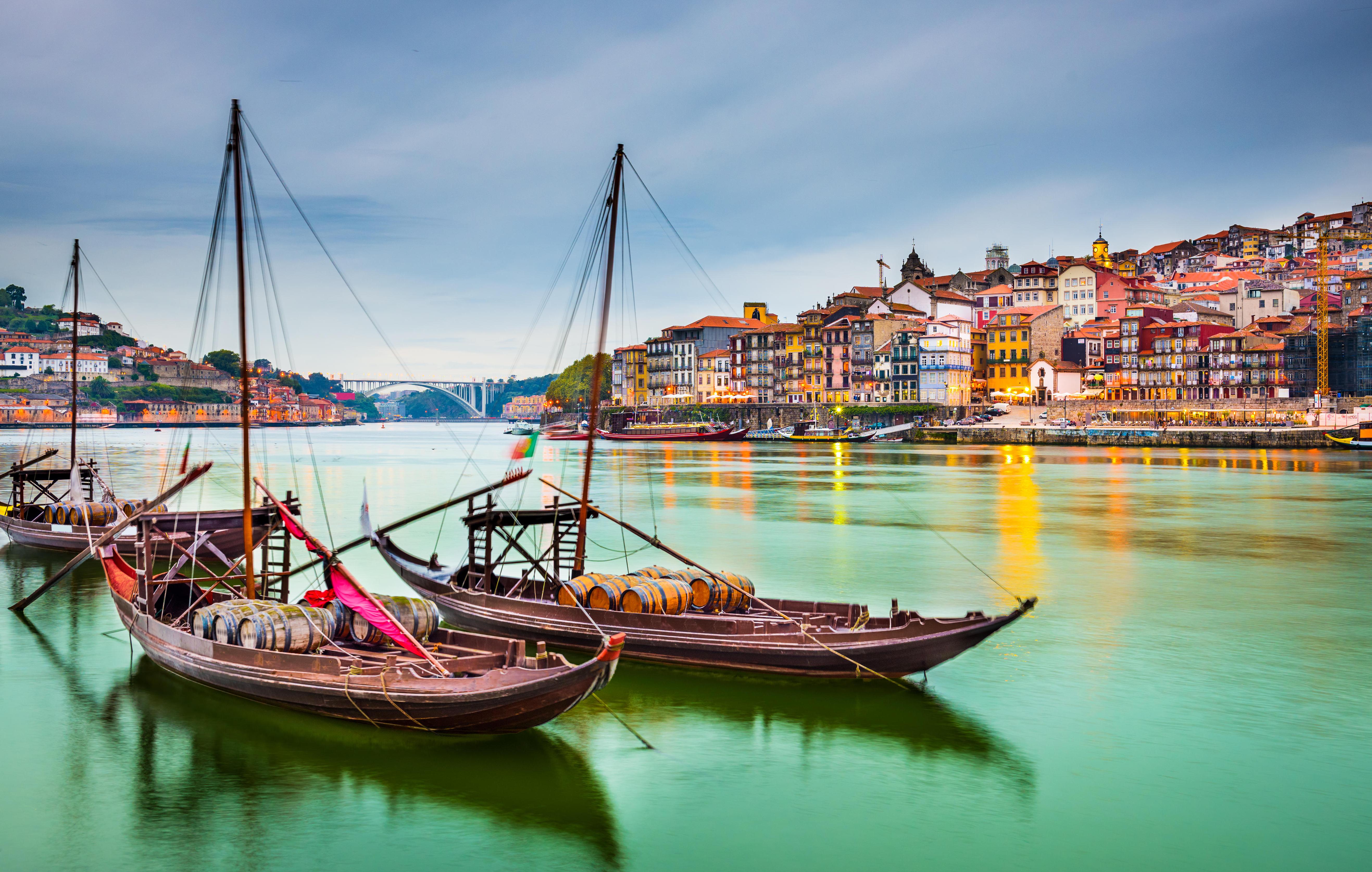 Porto, Portugal cityscape at dusk with Rabelo boats on the Douro River.